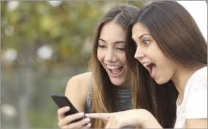 two young ladies giggling, watching video on cellphone